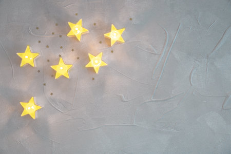 Christmas decorative garlands stars and candles glowing a light on texture background. Visualization...