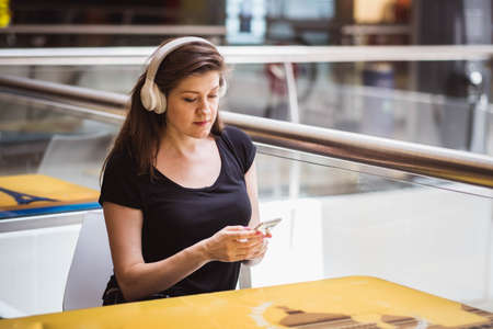 Portrait beautiful woman wearing white headphone enjoy music while her sitting in the park, Concept working outdoor and relax timeの写真素材