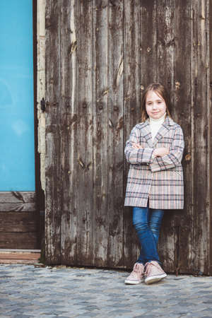 Portrait of adorable little fashionable girl outdoors near old fenceの写真素材