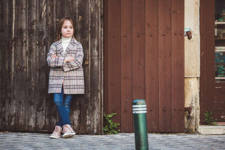 Portrait of adorable little fashionable girl outdoors near old fenceの写真素材