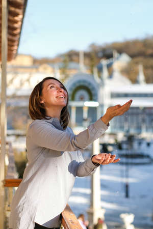 Happy young woman catching raindrops outside on the balconyの写真素材