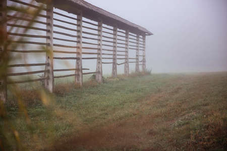 Wooden fence in foggy meadowの写真素材