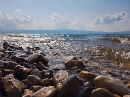 Waves on a stone beach, the texture of the transparent clear waters of the lakeの写真素材