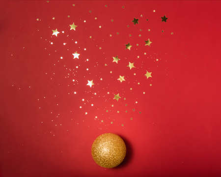 Golden shiny Christmas ball on a red background with sparkles golden stars.