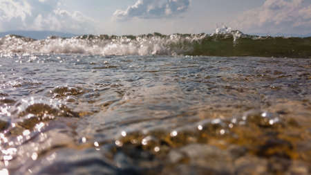 Waves on a stone beach, the texture of the transparent clear waters of the lake