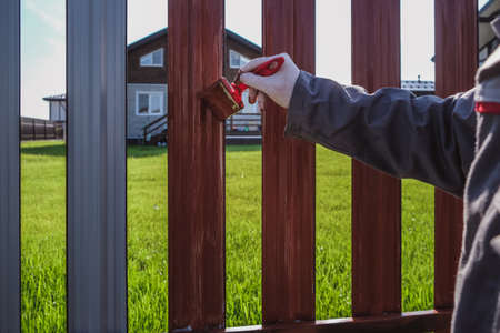 A man paints an iron fence in the gardenの写真素材