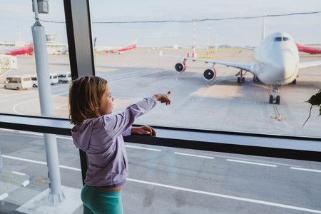 Little girl is looking to airplanes in airport waiting lounge in Moscowの写真素材
