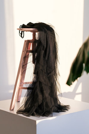 Luxurious black dress on a wooden chair with light in the background.の写真素材