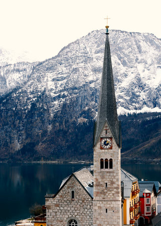 View of Hallstatt famous church with lake and Alps behind, Austria in winterの写真素材
