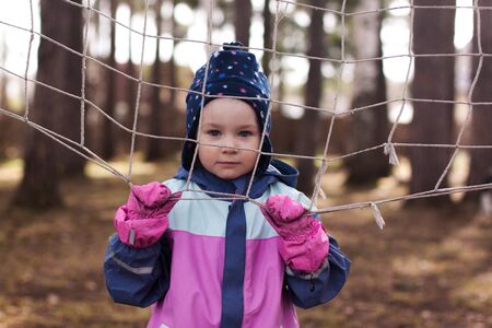 A girl holding on to a net in the woodsの写真素材