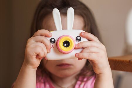 A girl takes pictures with a toy cameraの写真素材