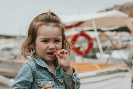 Girl in the port by the sea eating corn sticksの写真素材