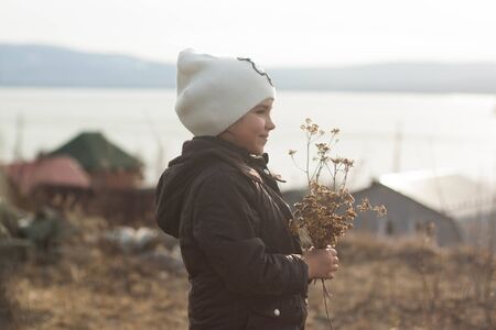 A girl stands on a mountain with dried flowers in her handsの写真素材