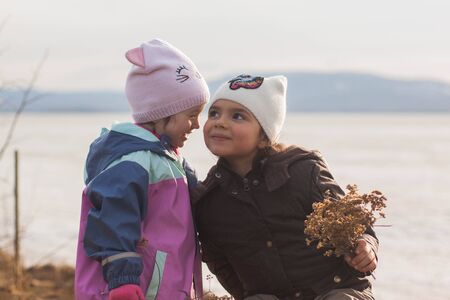 Two girls chat at sunset by the lakeの写真素材
