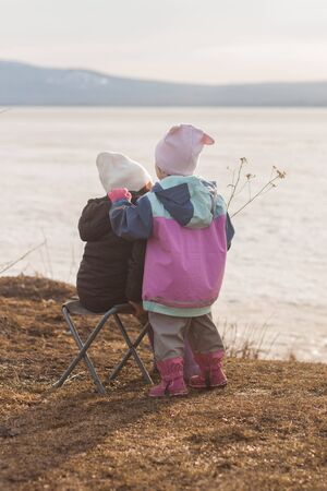 Two girls chat at sunset by the lakeの写真素材