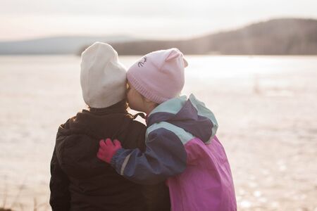 Two girls chat at sunset by the lakeの写真素材