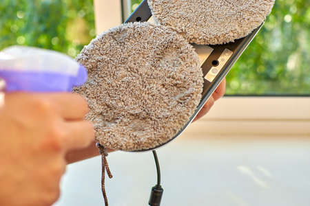 A man sprays window cleaner on a window cleaner robot. Preparing a window cleaner robot before work....