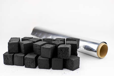 Charcoal and hookah foil on a white background. The concept of preparing a Shisha. A roll of...