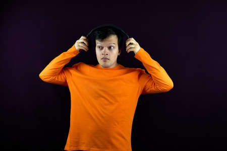 A man with headphones listens to music with a surprised look. A guy with a shocked and surprised...