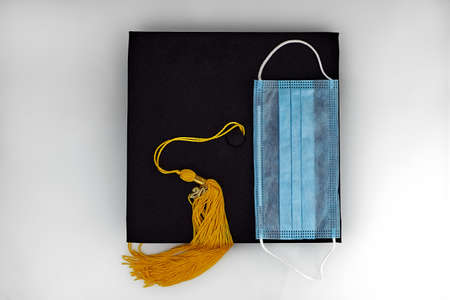 Graduate cap and medical mask on a white background. Virus protection for students, the concept of...