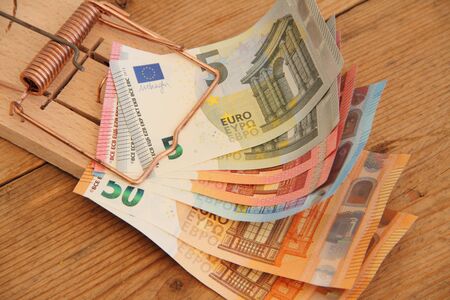 A wooden mousetrap with banknotes