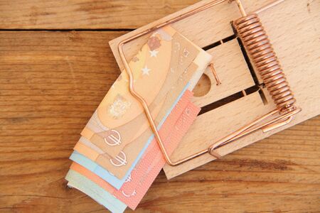 A wooden mousetrap with banknotesの写真素材