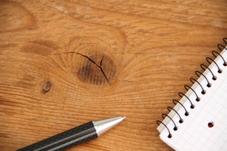 Empty writing pad with pen on a wooden tableの写真素材