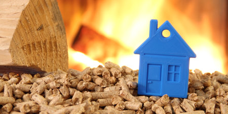 Wood stove with pellets with a toy house against fireの写真素材