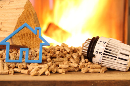 Wood stove with pellets with toy house and a radiator thermostat against fireの写真素材