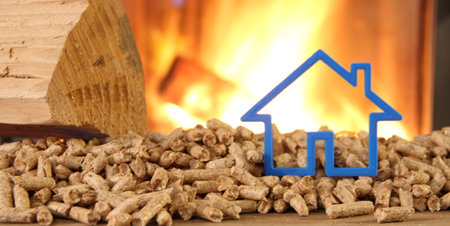 Wood stove with pellets with toy house against fireの写真素材