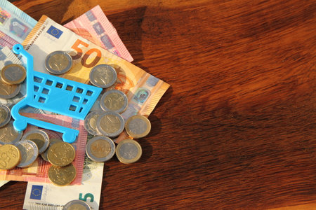 a small blue shopping cart on bills and coinsの写真素材