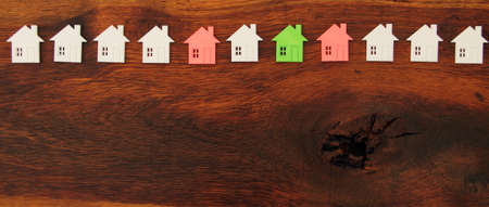 many small white houses, one red and one green house on a wooden board