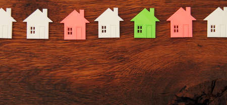 many small white houses, one red and one green house on a wooden boardの写真素材