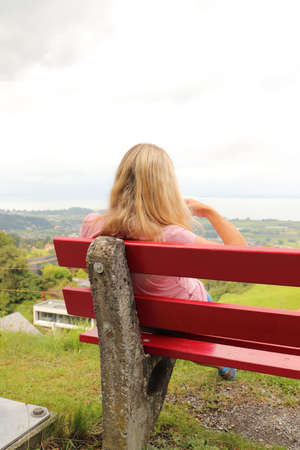 a blonde young pretty woman on a garden benchの写真素材