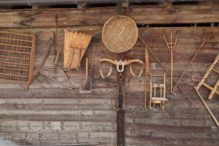 <p>an old wooden wall with an old agricultural tool</p>の写真素材