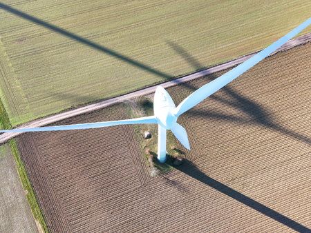 Aerial Wind Turbine Casting Shadow Across Agricultural Fieldsの写真素材