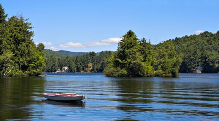 A lake in the mountains with a small boat in the foreground.の写真素材