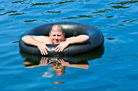 A man in water floating on an inner tubeの写真素材