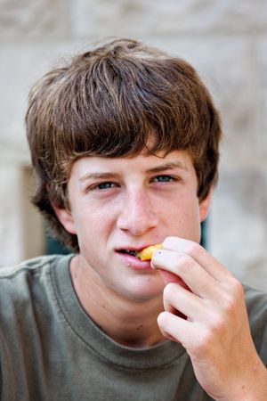 Portrait of a teenage boy eating a french fryの写真素材