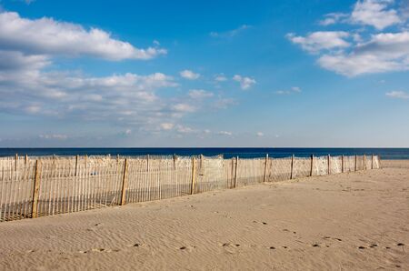 A wooden fence on the beach, The fence is on the sand in the foreground with the ocean and sky above.の写真素材