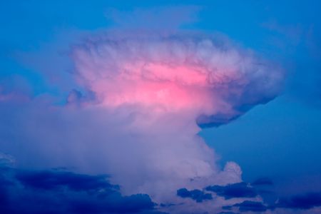 A cumulonimbus cloud that has formed an anvil-top shape. The last rays of light in the evening are causing a dramatic effect.の写真素材