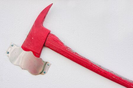 A red axe hanging on a white wallの写真素材