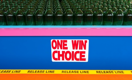 A game at the boardwalk where you toss rings trying to land them around the necks of bottles  The photo has rows of bottles as well as a sign that says One Win Choice in a colorful display の写真素材
