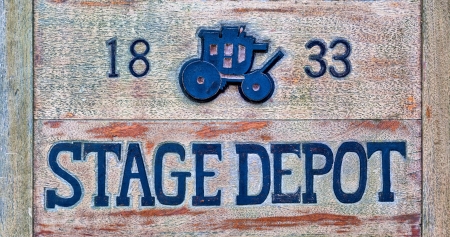 A stage depot sign made from wood. There is a picture of a stagecoach on it.のeditorial素材