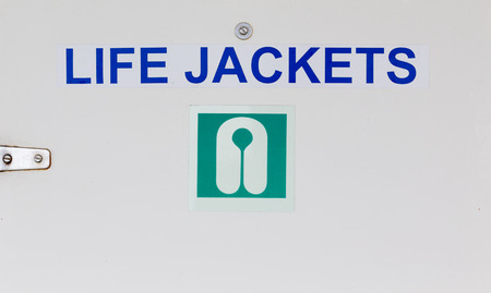 A Life Jackets Sign on a closet holding life jackets