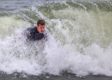 A young man bodysurfing in the ocean. His upper body is seen in the wave.の写真素材