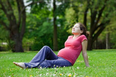 Young pregnant woman relaxing in the parkの写真素材