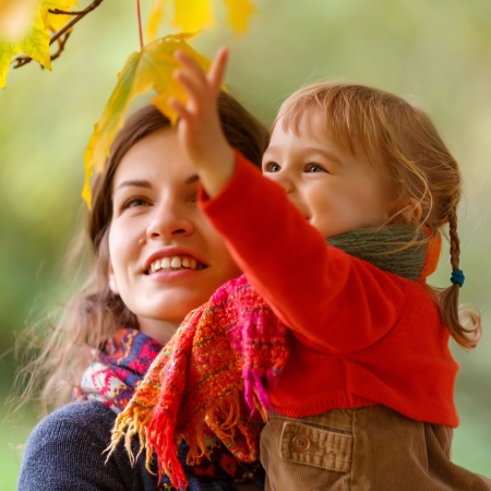 Little girl and her mother in the autumn parkの写真素材