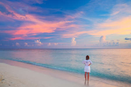 Young woman looking at sunset over oceanの写真素材