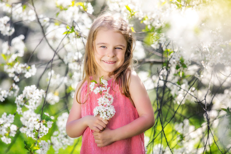 Happy little girl playing in spring cherry gardenの写真素材